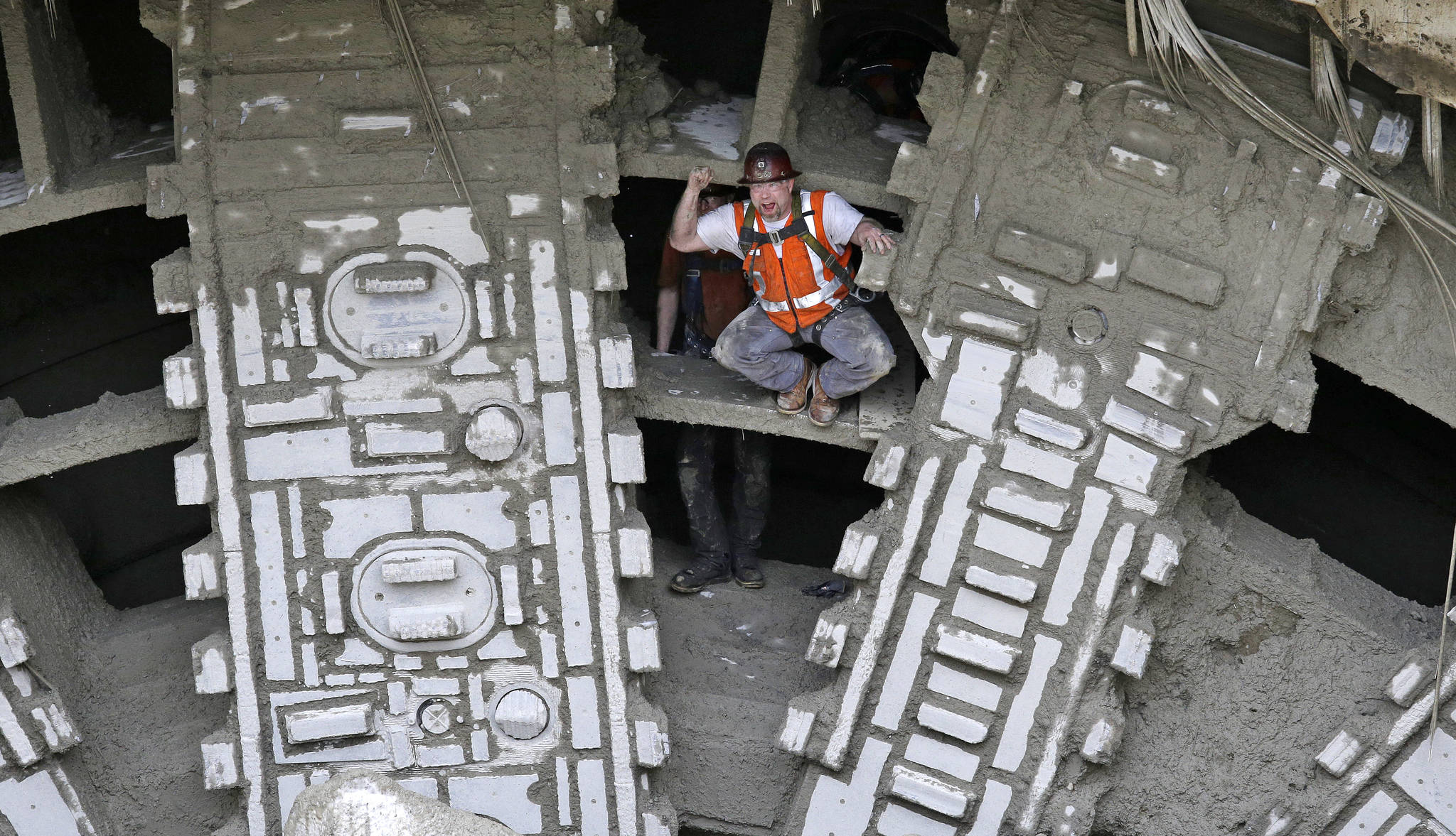 A worker pumps his fists as he stands between the cutting blades of a massive tunneling machine Tuesday under Seattle. (Elaine Thompson/The Associated Press)