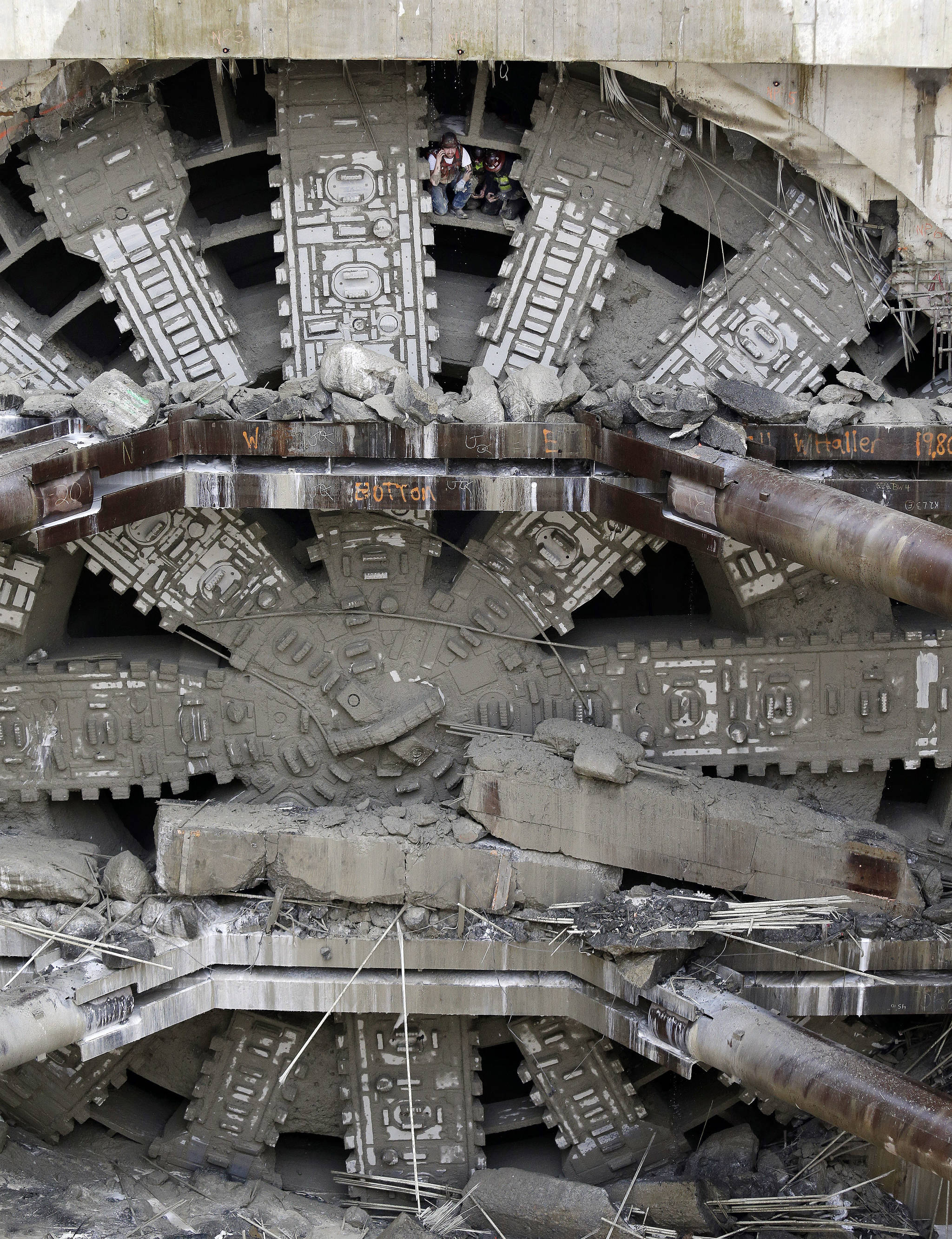A pair of workers climbs out between cutting blades near the top of a massive tunneling machine Tuesday under Seattle. (Elaine Thompson/The Associated Press)