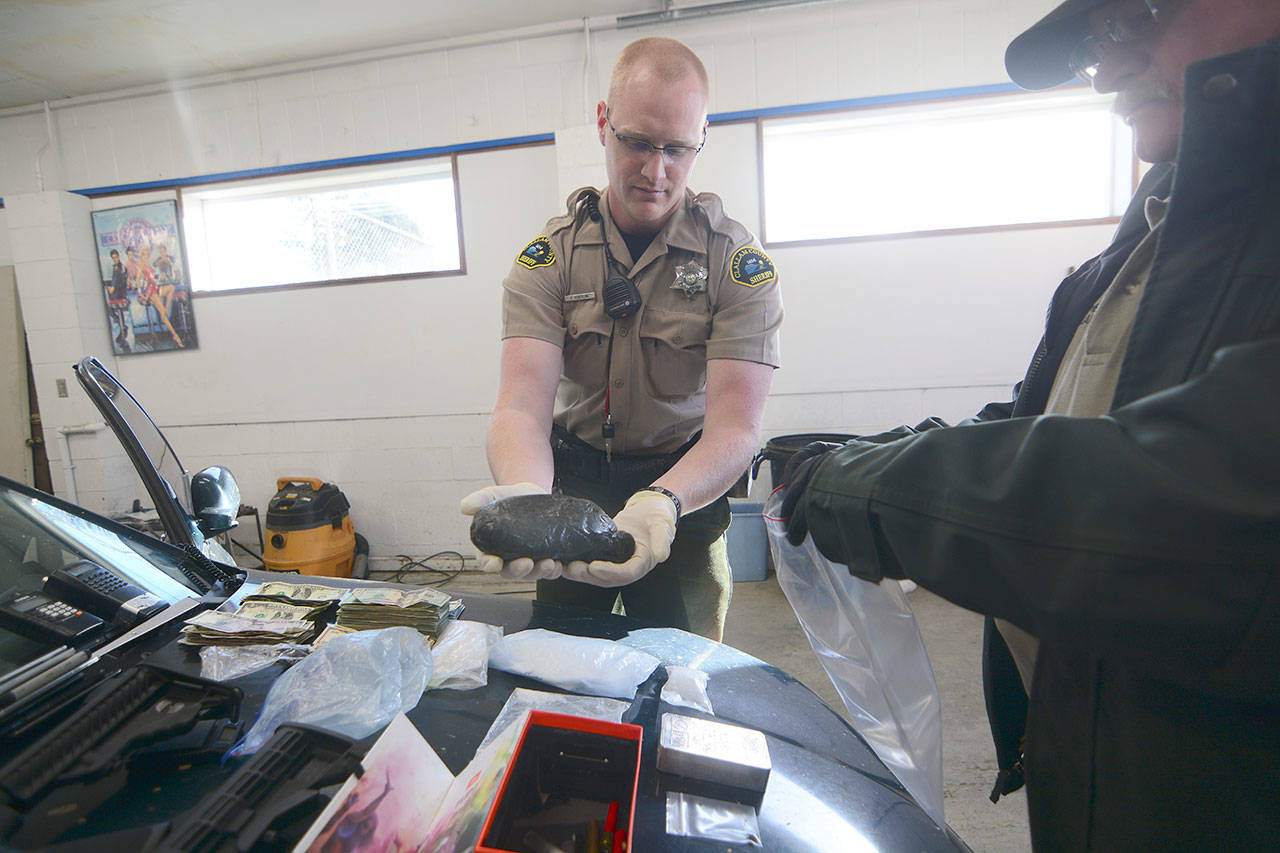 Clallam County Sheriff’s Deputy Paul Federline holds what he estimated to be about two pounds of heroin while searching the car of someone who was reportedly driving recklessly on U.S. Highway 101 in Port Angeles on Sunday. (Jesse Major/Peninsula Daily News)