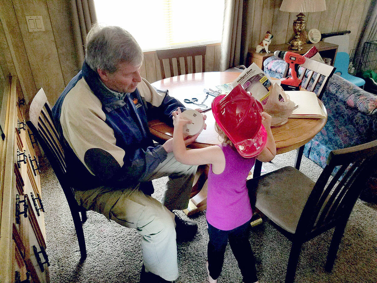 Rotarian Rob Onnen instructs a young girl on how to test her smoke alarm and what to do in an emergency should the detector sound. (Clallam County Fire District No. 2)