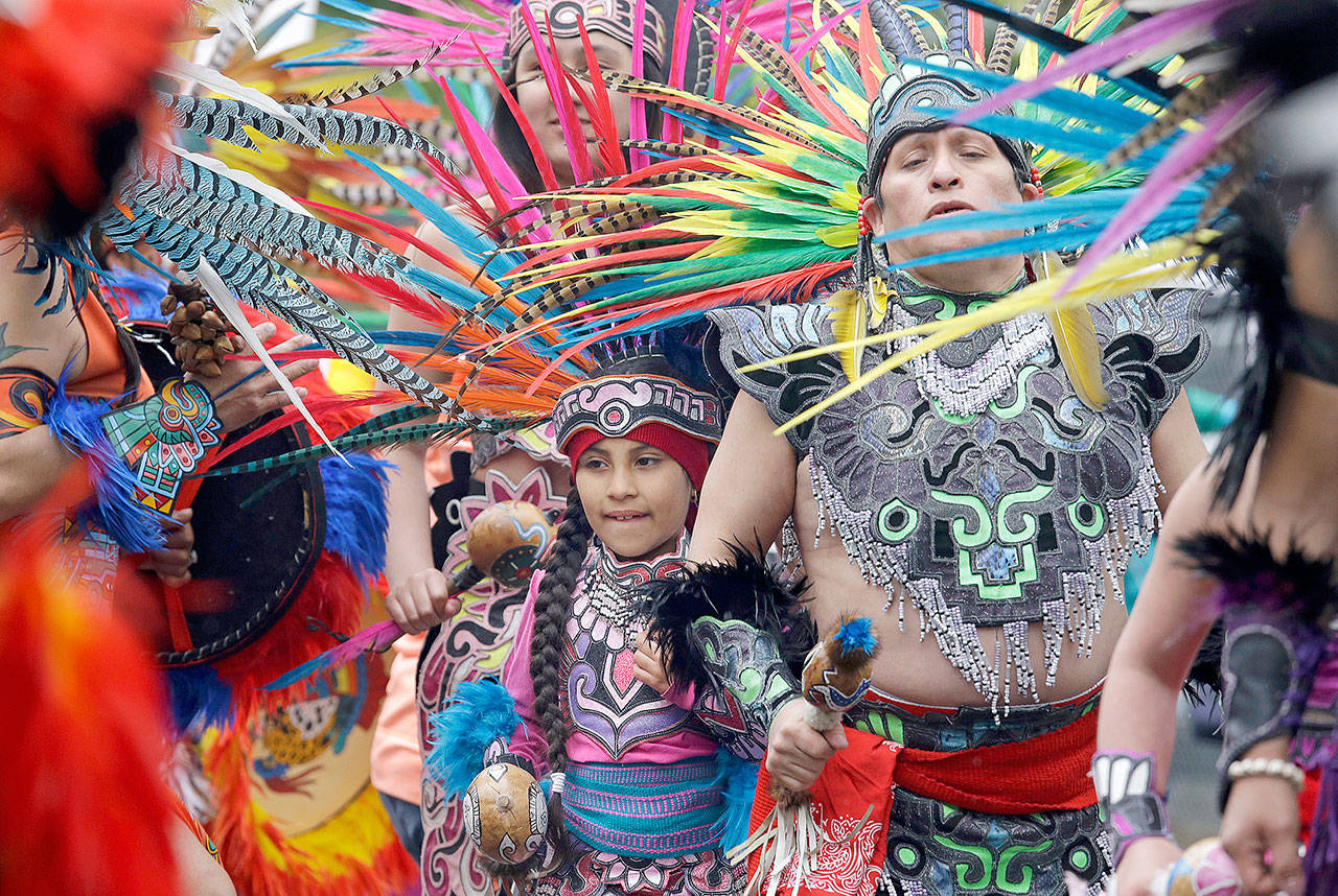 Members of Ce Atl, an Aztec-inspired spiritual and cultural preservation group, dance near the front of a march for worker and immigrant rights at a May Day event Monday in Seattle. (Elaine Thompson/The Associated Press)