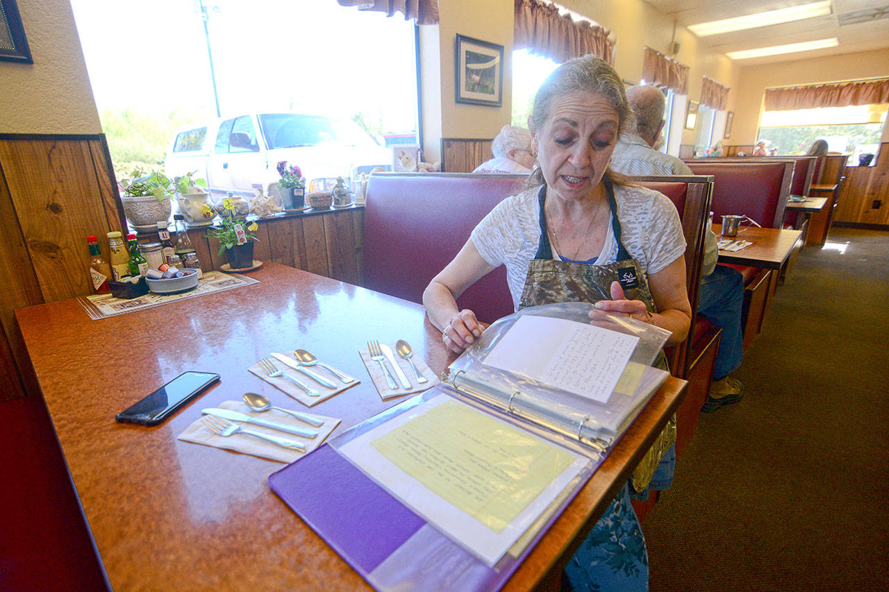Roxanne Olsen, who owns the Blackberry Cafe in Joyce, looks through letters from people who have donated to “Andy’s Fund.” (Jesse Major/Peninsula Daily News)