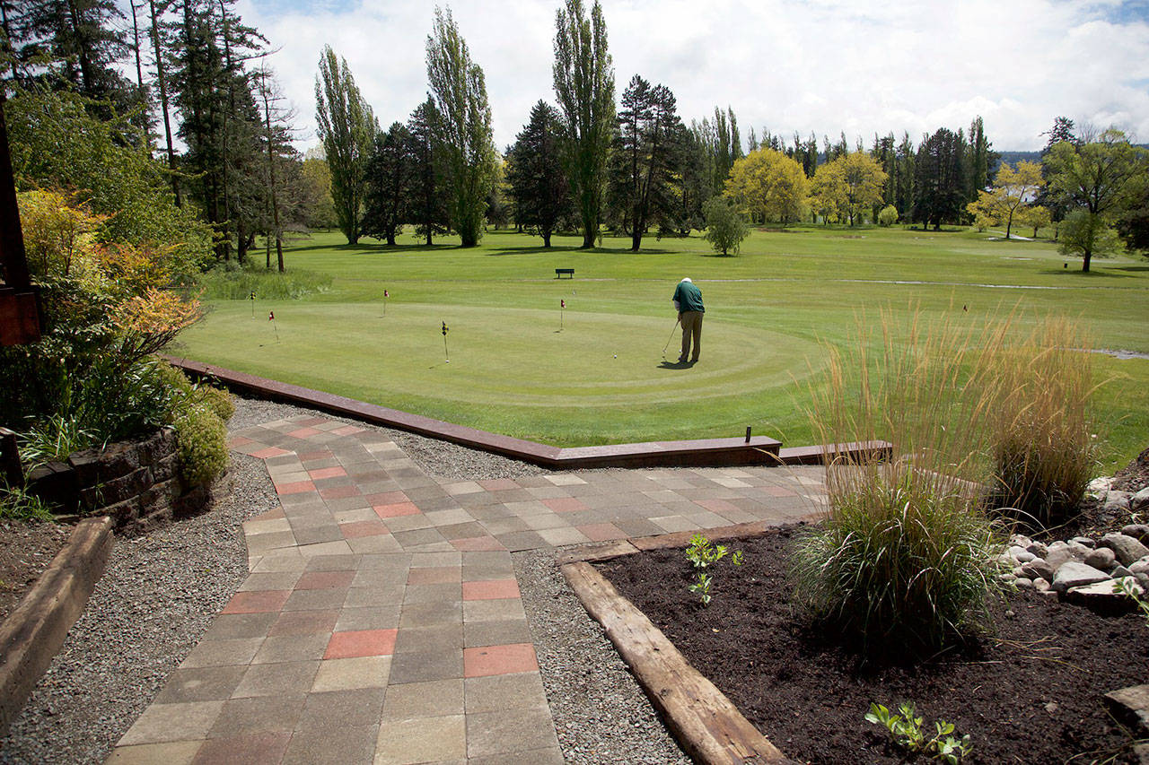Steve Mullensky/for Peninsula Daily News PGA Golf Professional, Jeff Kent, practices putting on the green after new tiled walkways and landscaping work was recently finished. Additional landscaping will be installed at a later date.