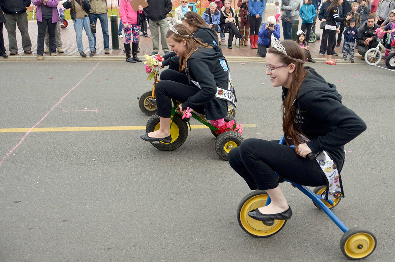 Rhododendron Festival royalty — from foreground, Princess Sarah Smith, Princess Taylor Tracer and Queen Lauren Montgomery — compete in the annual tricycle race, just one in a week full of events in Port Townsend. (Cydney McFarland/Peninsula Daily News)