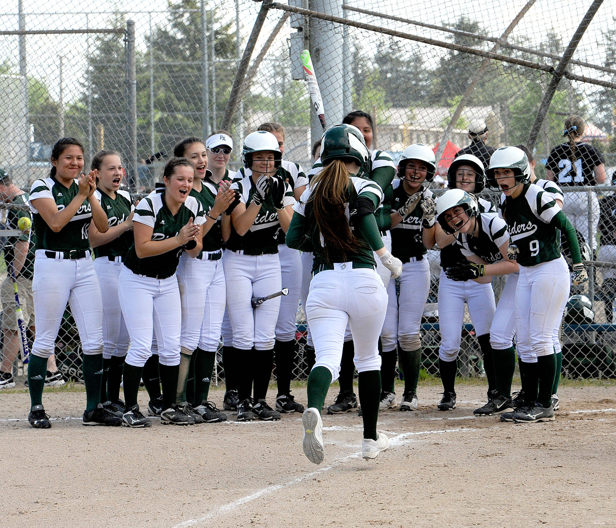 Lonnie Archibald/for Peninsula Daily News Port Angeles players mob Lauren Lunt at home plate after Lunt hit a grand slam in the first inning of the Roughriders’ 16-0 win Saturday over Orting. The victory sent the Riders to the West Central District 3 championship game.