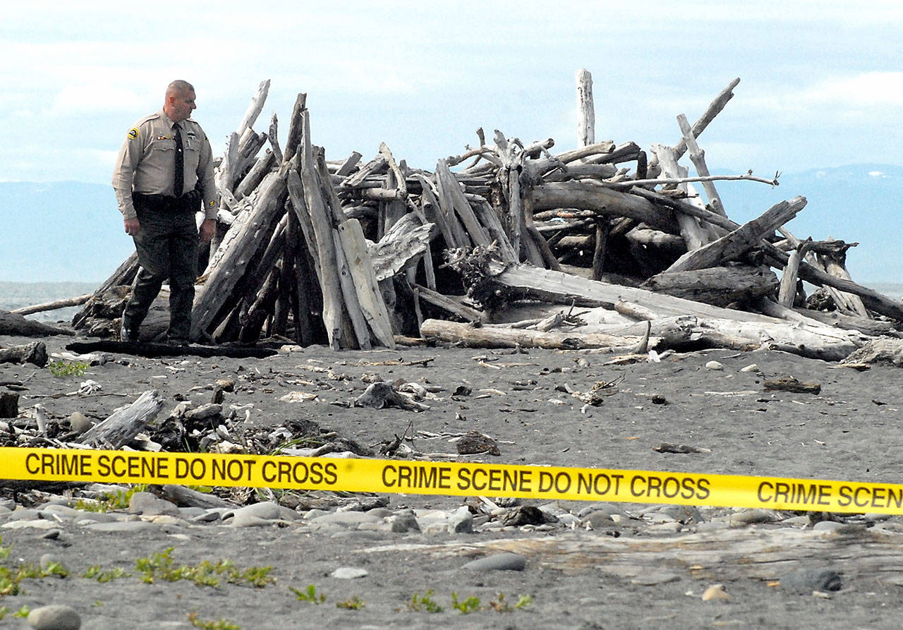 Clallam County Sheriff’s Deputy Michael Leiter looks over a driftwood structure near the spot where an unignited military marker flare was discovered near the mouth of the Elwha River west of Port Angeles on Friday. (Keith Thorpe/Peninsula Daily News)