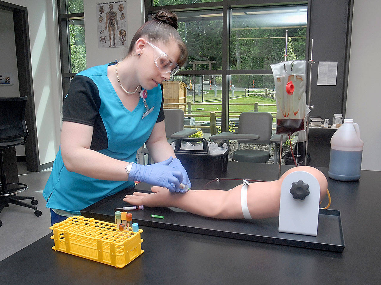 Student medical assistant Christina Wommack of Port Angeles practices her phlebotomy skills on an artificial arm Thursday in a clinical lab seminar classroom in the newly constructed Allied Health & Early Childhood Education Building on the Port Angeles campus of Peninsula College. (Keith Thorpe/Peninsula Daily News)