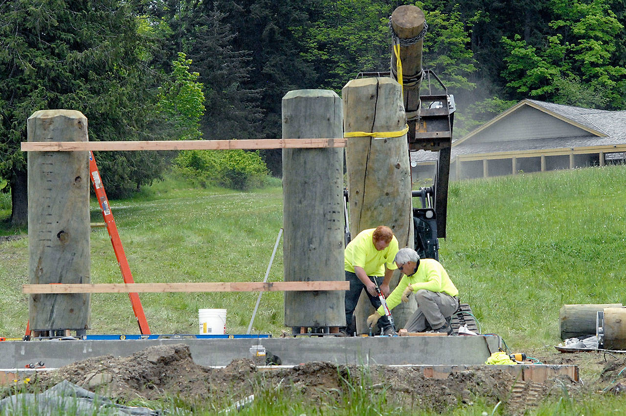 Justin Danbrosio, left, and Larry McCullough of Pinedale, Wyo.-based Wind River Stone Scapes install pieces Thursday for what will become a new entrance sign to Olympic National Park on the lawn in front of the park’s Port Angeles visitor center. (Keith Thorpe/Peninsula Daily News)