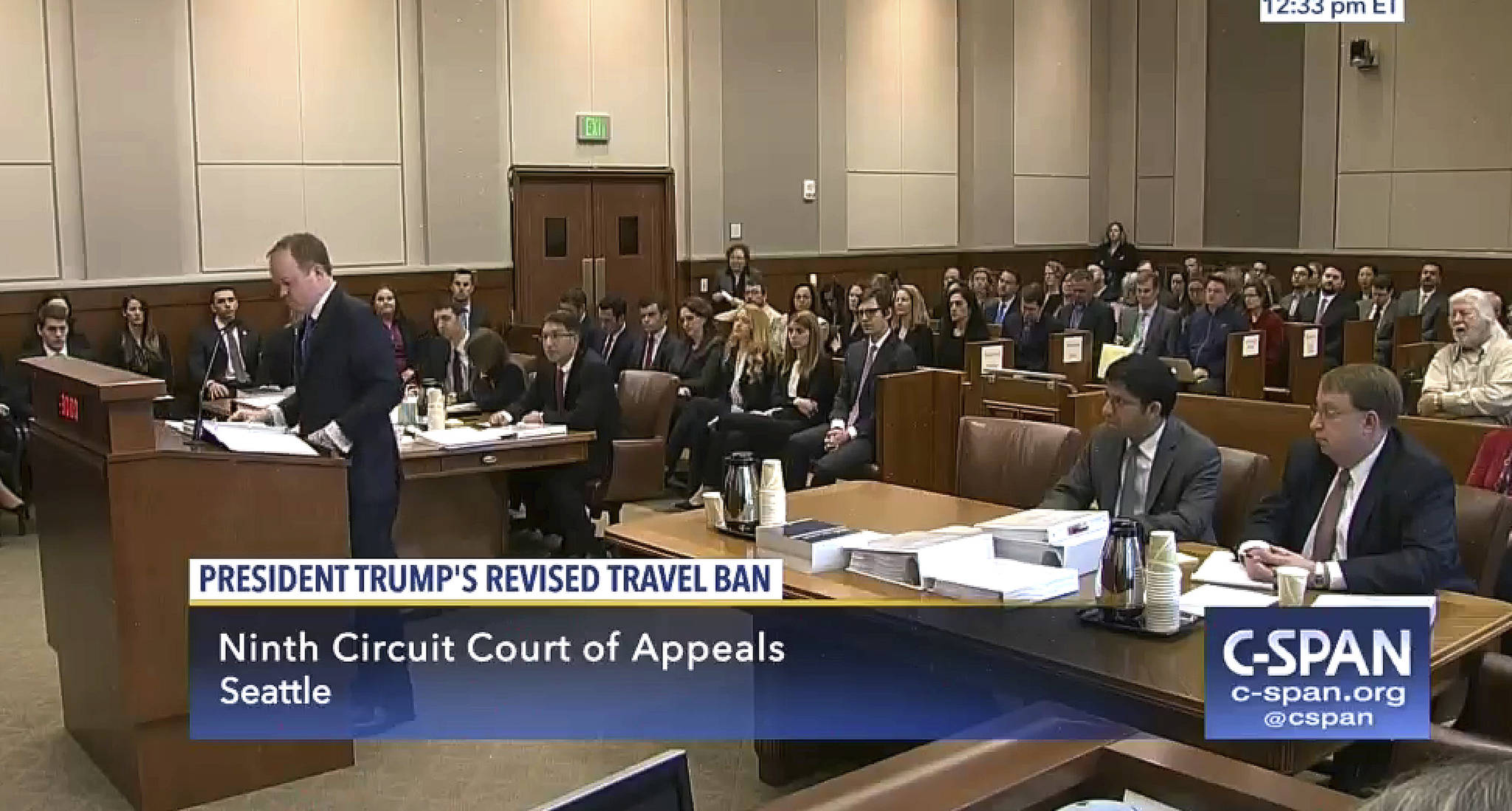 In this image made from a C-SPAN video, Acting Solicitor General Jeffrey Wall, standing at left, presents his arguments during a 9th Circuit Court of Appeals panel in Seattle on Monday. (CSPAN via AP, Pool)