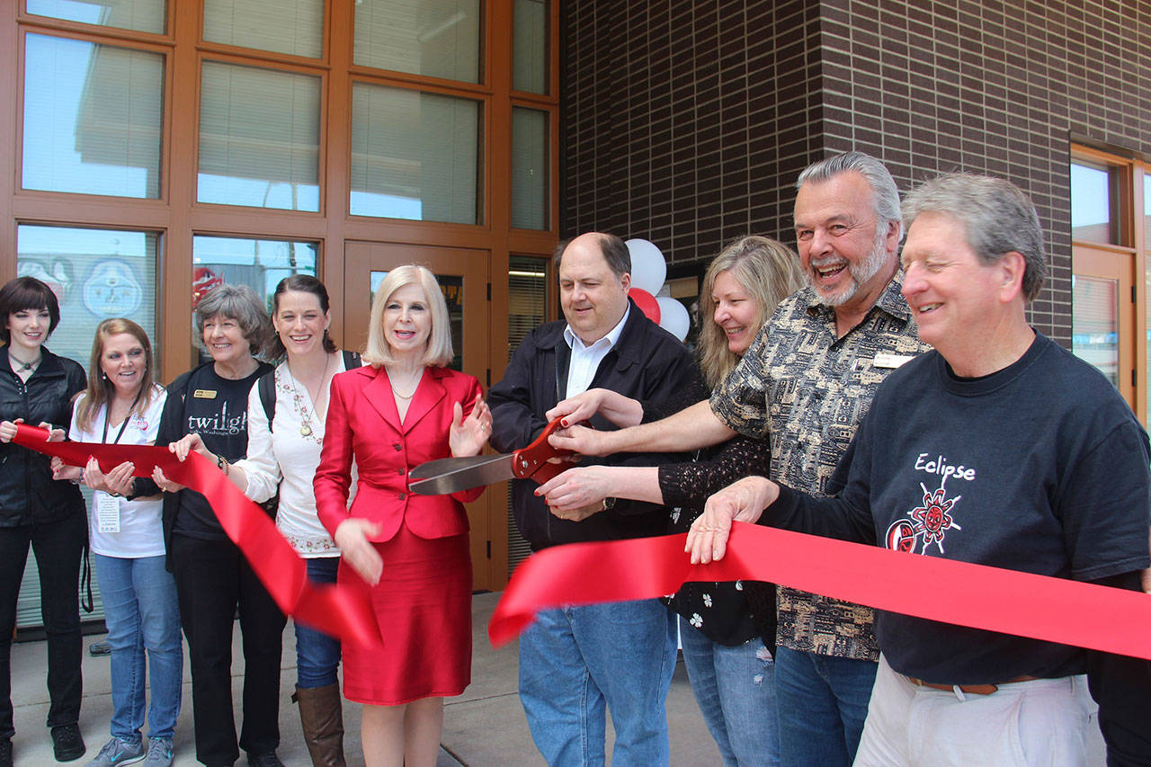 From left, Jessica Hagen, Kelly Grable, Forks Visitor Information Center volunteer Marcia Yanish, Katryna Harris, Port Angeles Deputy Mayor Cherie Kidd, Forks Mayor Bryon Monohon, Forks Chamber of Commerce Executive Director Lissy Andros, Forks Chamber of Commerce President Don Grafstrom and Mike Gurling take part in a ribbon cutting Saturday for the Forever Twilight in Forks Collection at the Rainforest Arts Center. Hagen plays Alice Cullen from the Twilight series during the Forever Twilight in Forks Festival. Grable and Harris are Twilight fans who live out of the area and assisted with getting the collection ready, while Gurling worked with the Visitor Information Center when Twilight started gaining popularity. (Christi Baron/Olympic Peninsula News Group)