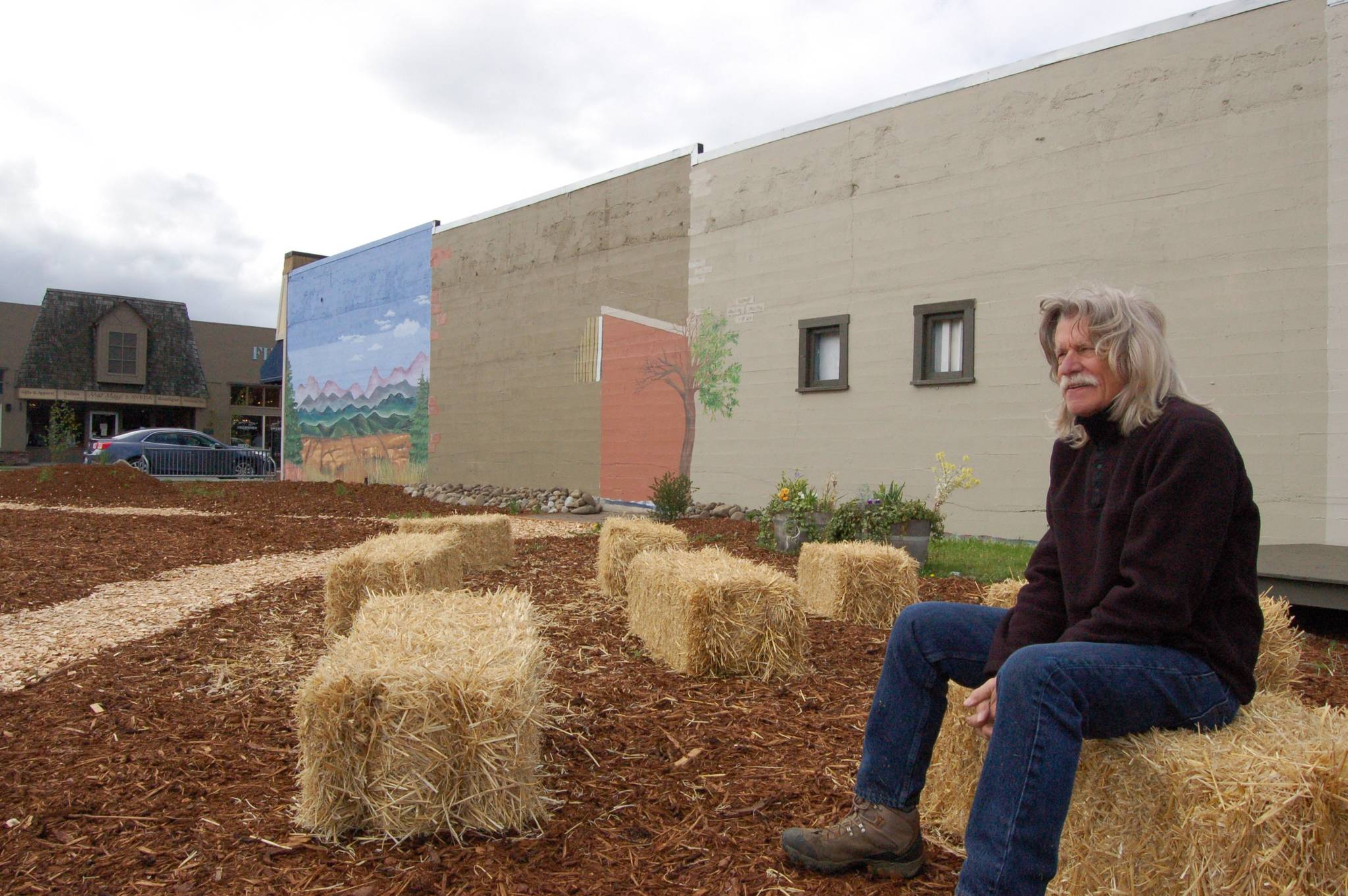 Ken Stringer, head organizer of Whimsy Park, sits on one of the straw bales installed at the new temporary park located on East Washington Street between Jose’s Famous Salsa and The Rusting Rooster in Sequim. (Erin Hawkins/Olympic Peninsula News Group)