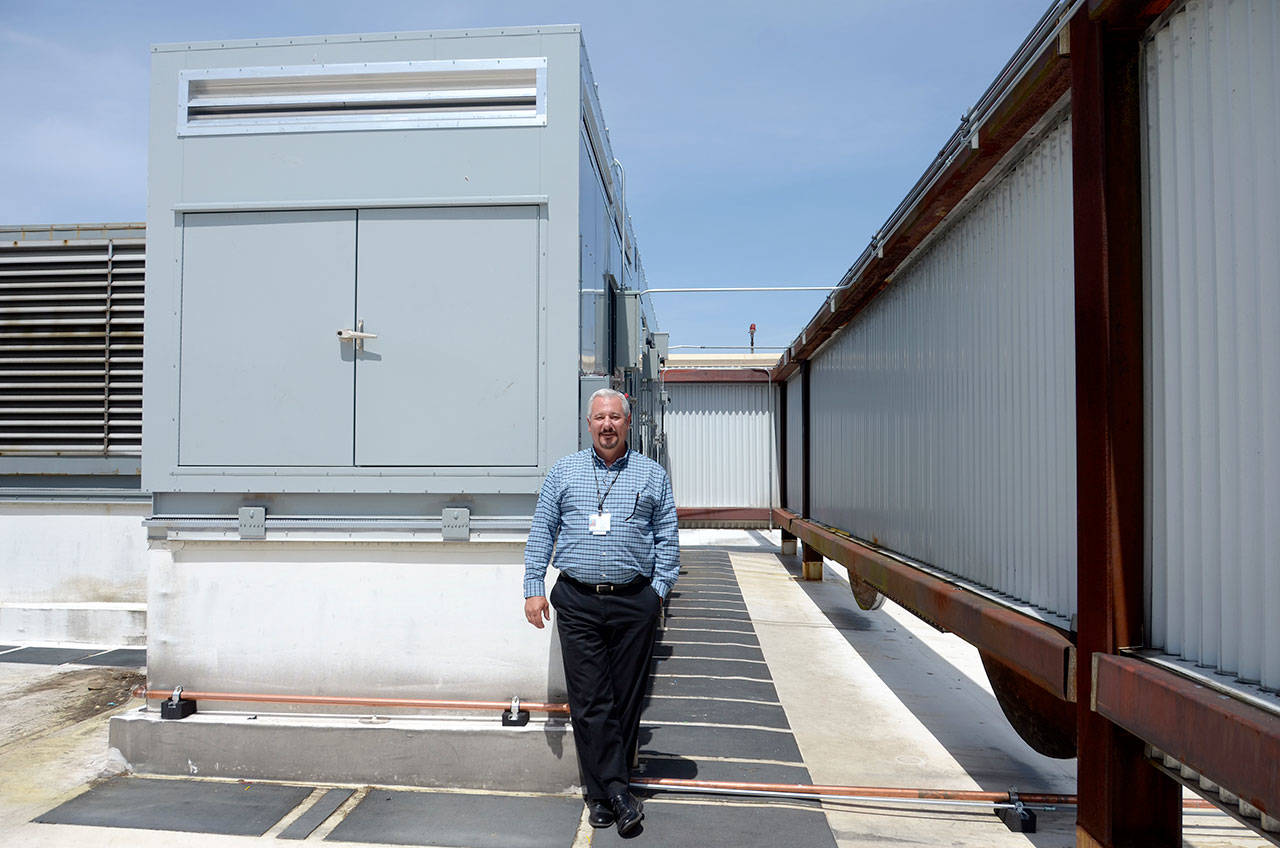 Chris O’Higgins, the director of facilities at Jefferson Healthcare, stands next to the new air handling unit that heats, cools, monitors humidity and kills germs in the air in the hospital’s surgical units. (Cydney McFarland/Peninsula Daily News)