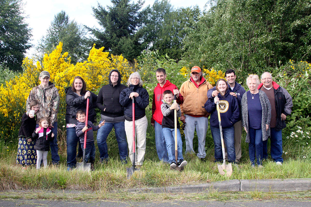 Homebuilders in the Mutual Self-Help Housing Program of the Peninsula Housing Authority pose at a ceremonial groundbreaking on West 15th Street in Port Angeles. From left are Justin Smith with Caidence and Caesyn Smith, Autumn Clark and Parker Silva, Alexis Biss, Linda Dolan, Robert Kalfur and Kayden Kalfur, Willy Feeney, Debbie and Jeremy Kirkland, and Karen and Jim Williams. (Dave Logan/for Peninsula Daily News)
