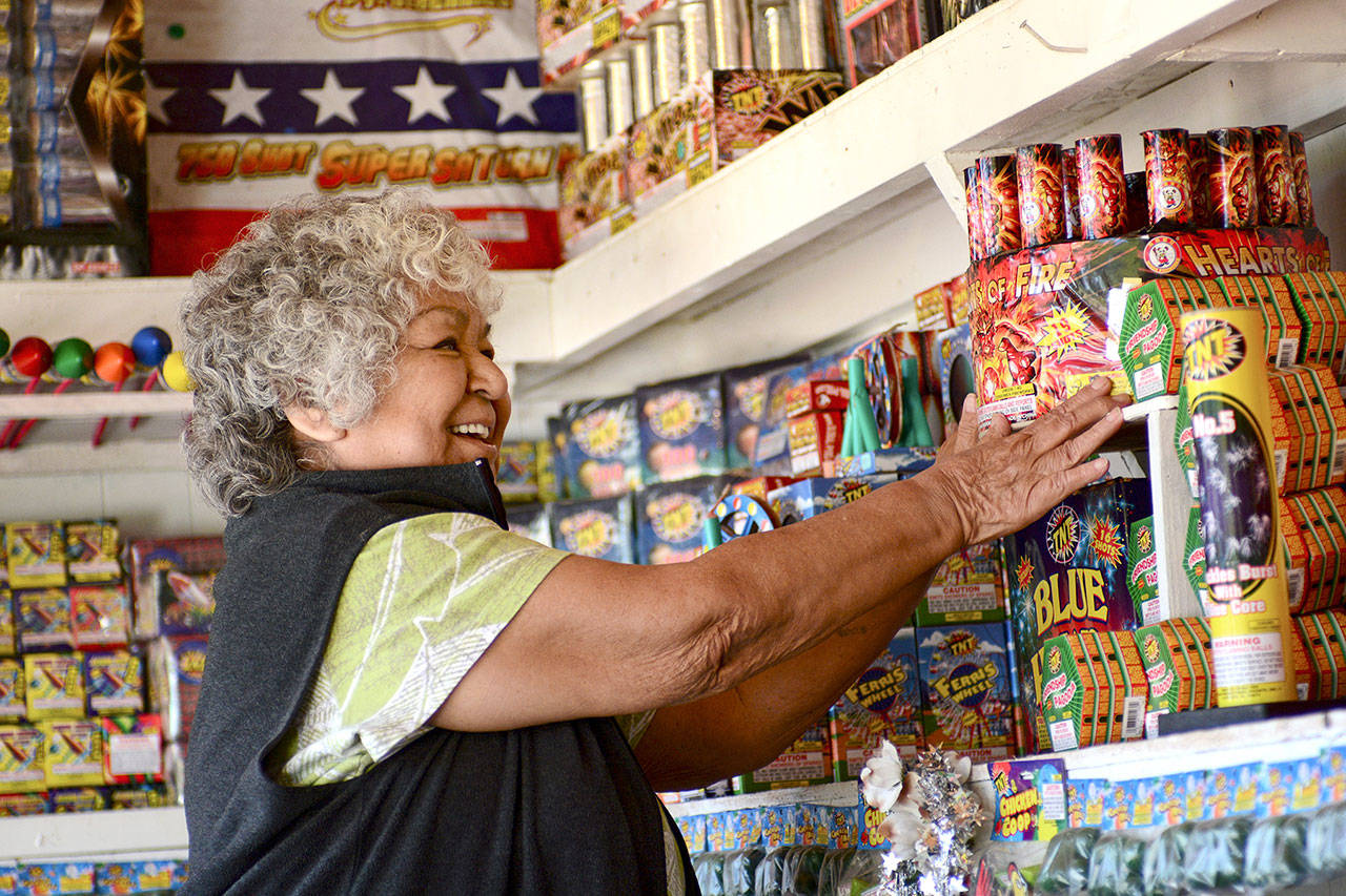 Margie Macias arranges fireworks at her fireworks stand, Margie Fireworks, on the Lower Elwha Klallam Tribe reservation on Tuesday. State-licensed fireworks stands can begin selling fireworks at noon today. (Jesse Major/Peninsula Daily News) ​
