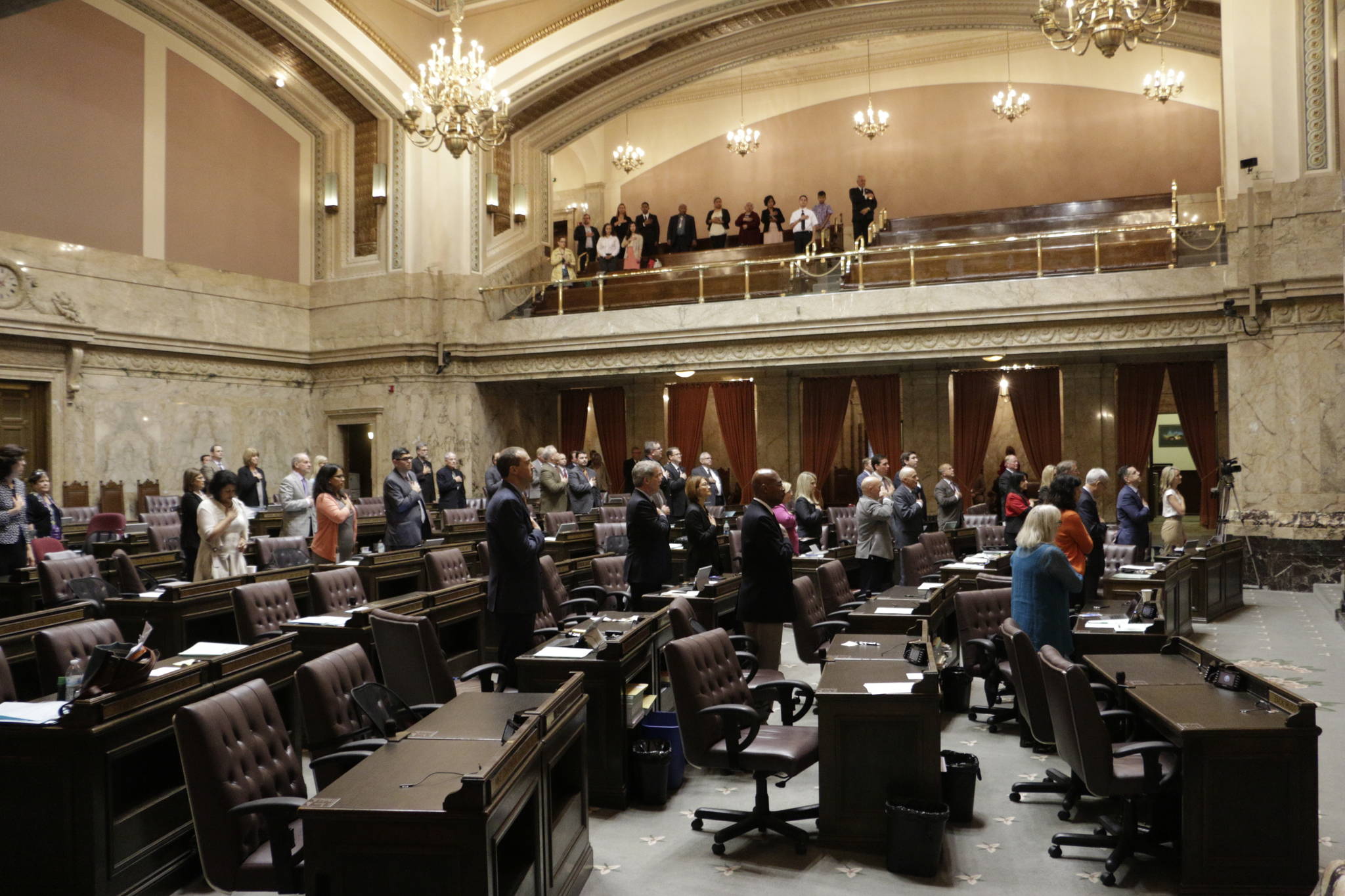 Lawmakers at the House stand during the Pledge of Allegiance on Tuesday in Olympia. The Legislature must send a new two-year budget this week or else risk a partial government shutdown. (Rachel La Corte/The Associated Press)