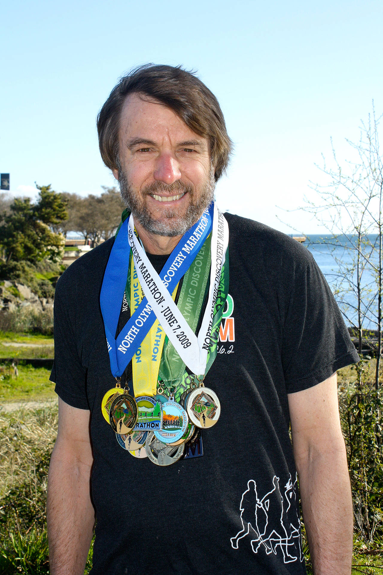North Olympic Discovery Marathon                                Port Angeles’ Tom St. Amand wears his North Olympic Discovery Marathon medals. St. Amand has completed all 14 marathons to date, and will run in Sunday’s 15th annual race.