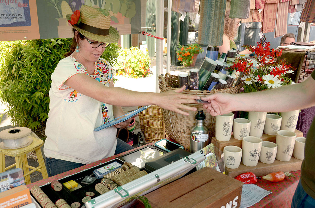 Farmers Market Coordinator Amanda Milholland hands out market tokens at the Saturday market in Port Townsend, the only one of the three markets overseen by the Jefferson County Farmers Market Association that is not being eyed for moving to a new location. (Cydney McFarland/Peninsula Daily News)