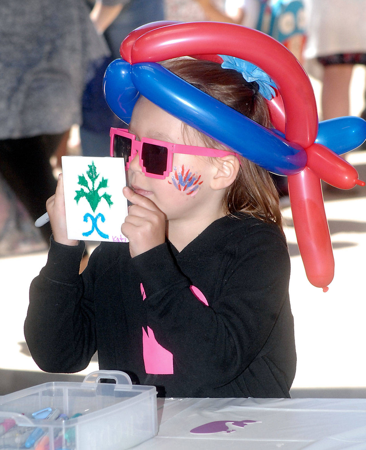 Katrina Peterson, 7, of Port Angeles shows off a ceramic tile she decorated at a kids activity center on Independence Day at The Gateway transit center pavillion in Port Angeles. (Keith Thorpe/Peninsula Daily News)