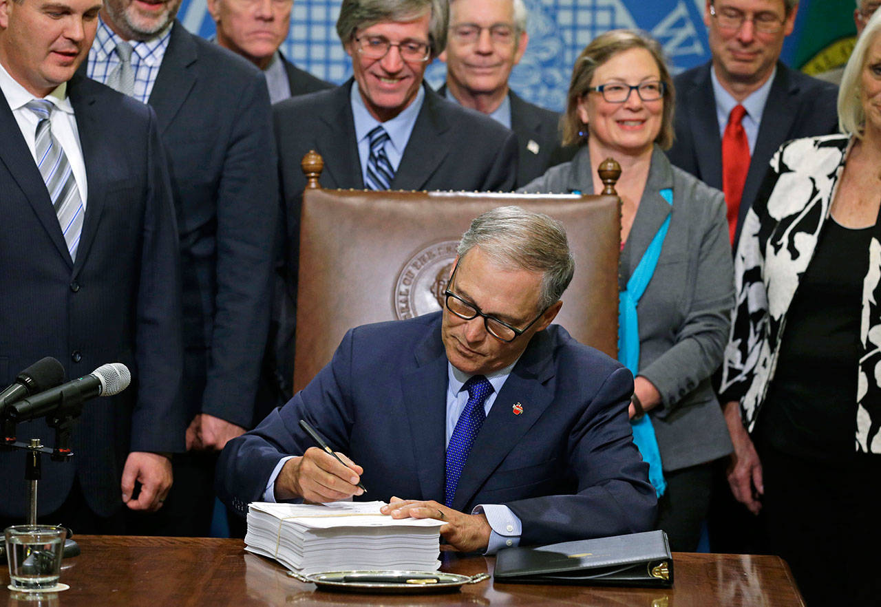 Gov. Jay Inslee signs a new two-year state operating budget Friday at the Capitol in Olympia. The budget was approved by the Legislature earlier in the day, just in time to avert a partial government shutdown. (Ted S. Warren/The Associated Press