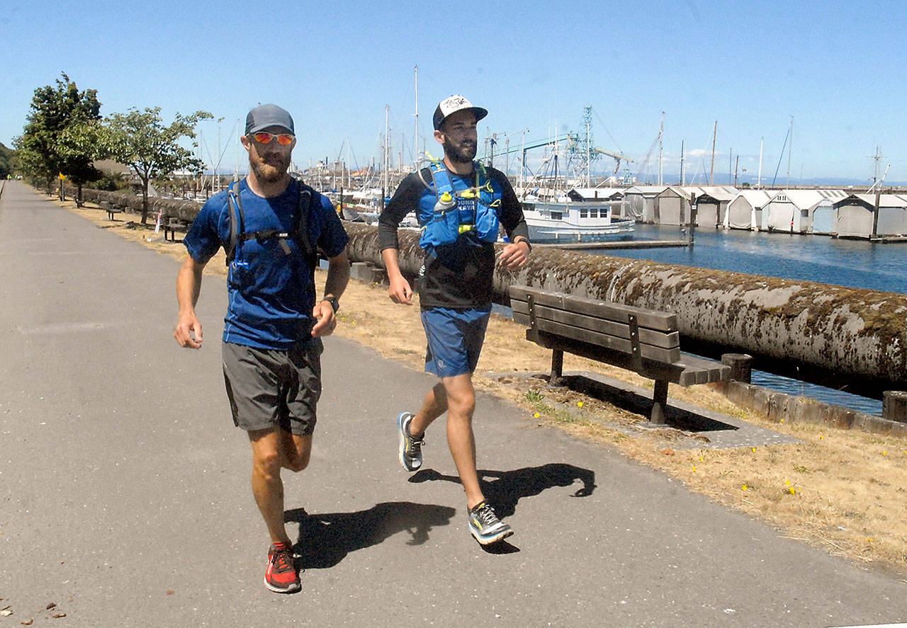 The Rev. Joe DeScala, left, and running companion Kelley Burns, who joined DeScala for part of his journey, jog along the Waterfront Trail in Port Angeles, nearing the completion of DeScala’s fund-raising journey around Washington state. (Keith Thorpe/Peninsula Daily News)