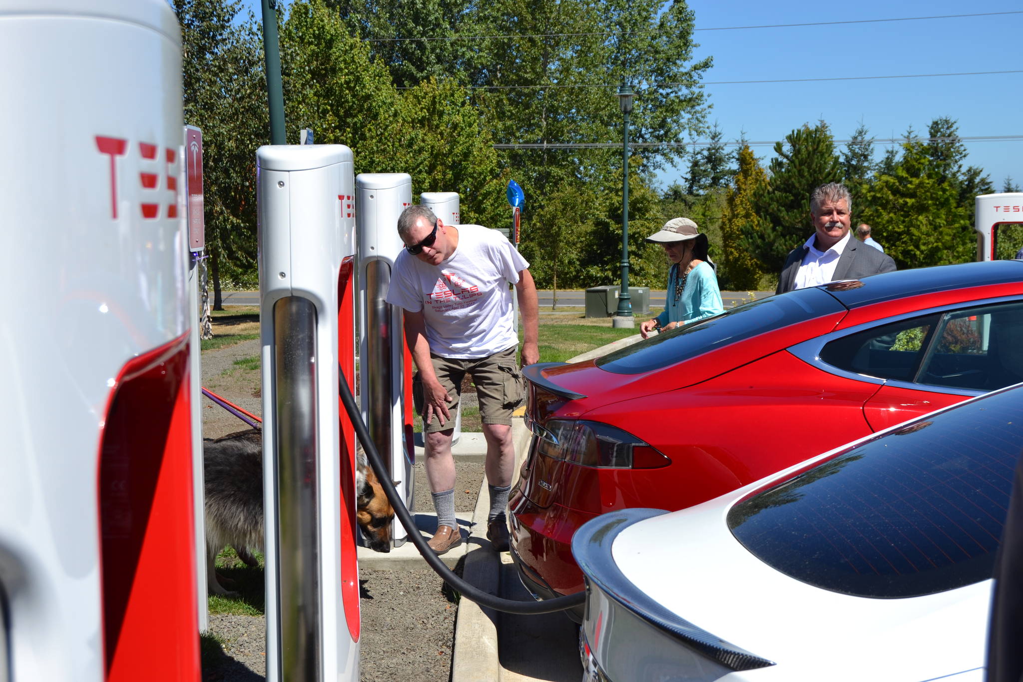 Matthew Nash/Olympic Peninsula News Group Brick Ayola of Port Angeles looks at two Tesla cars at the ribbon-cutting for the new Supercharger station at the Sequim Holiday Inn Express & Suites. Ayola said he’s owned his Tesla for close to five years and drove to the area from Chicago. He’s looking forward to a Supercharger station opening in Forks so he can make the loop around the Olympic Peninsula.