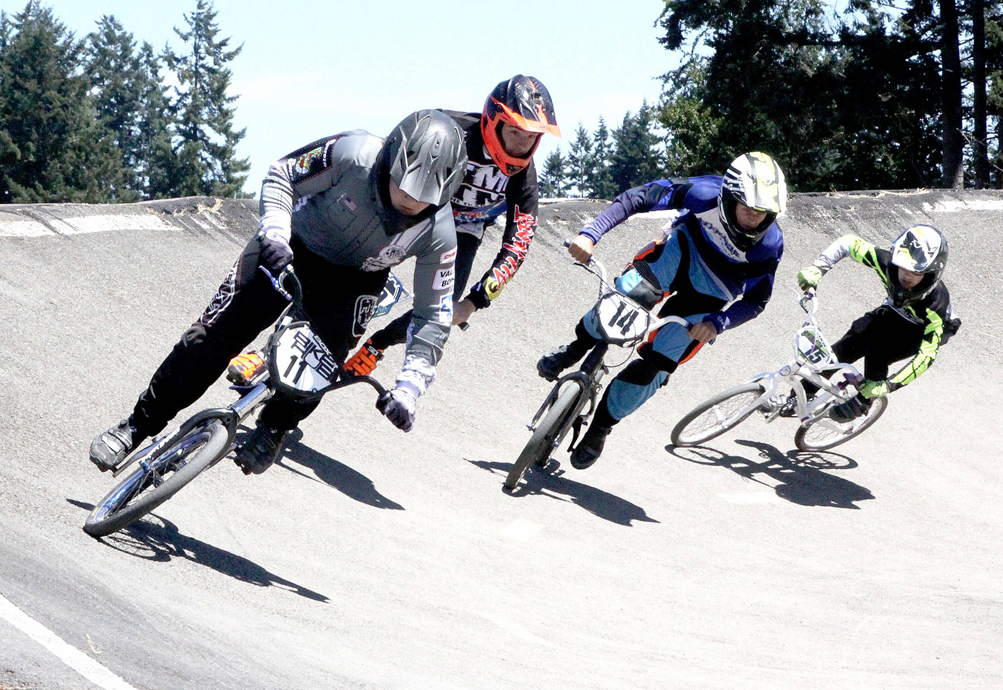 A qualifier for the Washington state BMX championships was held Sunday at the Lincoln Park BMX track. Over 200 riders from ages 3 to 70 entered the various “motos” to try to earn their way to the state championships in Richland over Labor Day weekend. In this face, from left are Bailey Conners (11) from Puyallup, #14 is Casey Cramer (14) from Des Moines and Preston Stevens (15) of Milton rounding the big curve on the track. (Dave Logan/for Peninsula Daily News)