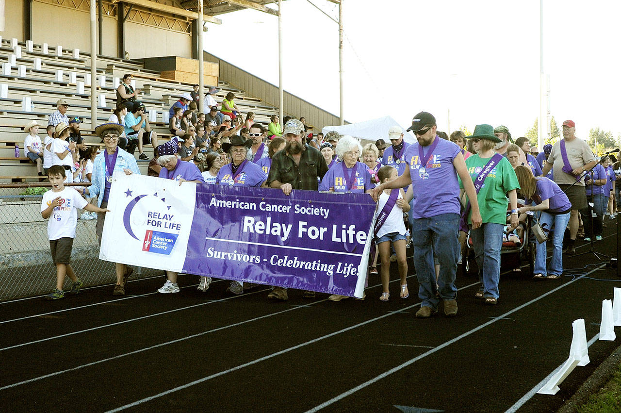 Relay attendees hoist the American Cancer Society’s banner as they walk in the survivor’s celebration during Forks’ 2016 Relay for Life. (Cindy Mesenbrink)