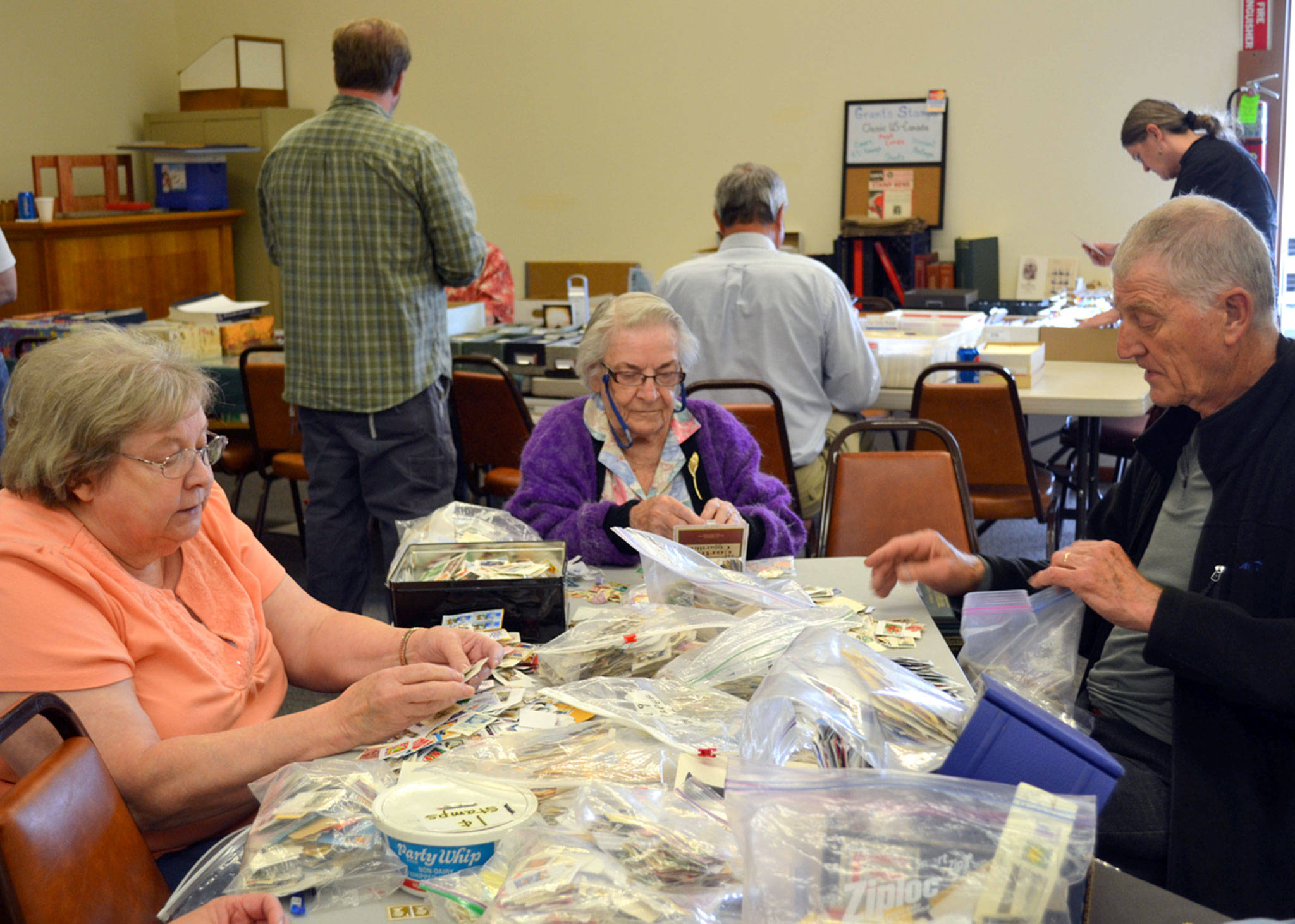 Stamp collectors, from left, Jan Schultz of Port Angeles, June Mennell of Sequim and John Plantinga of Victoria, B.C., search for stamps in the penny pile at the Strait Stamp Show in 2015 in the Sequim Masonic Lodge. This year’s 24th annual show is Saturday with 15-plus vendors and plenty of stamps to go around. (Matthew Nash/Olympic Peninsula News Group)