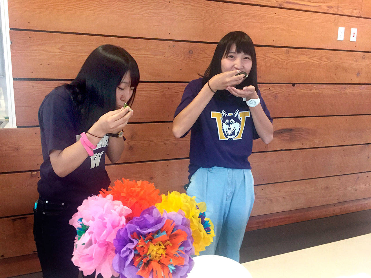 Akane and Hina, high school students from Ichikawa, Japan, who declined to provide their last names, eat temaki sushi at a potluck for the sister cities student exchange. (Cydney McFarland/Peninsula Daily News)