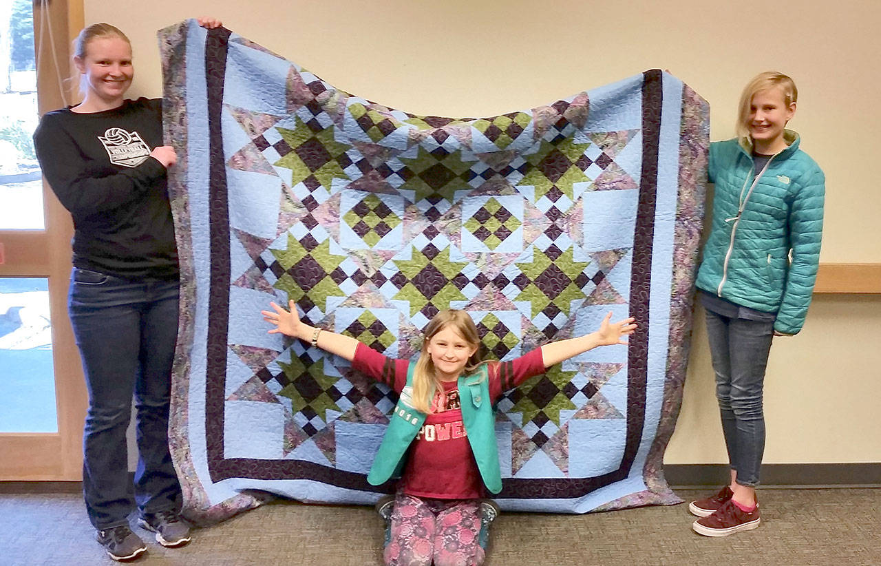 First prize in a Paws-N-Claws 4-H Club raffle at the Jefferson County Fair is a quilt. Shown with it are, from left, Katie Bailey, Layla Franson and Nadia Fisch.