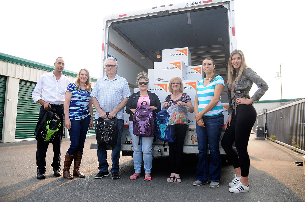 Foster children advocates help unload a donation of 250 backpacks at All About Storage on Aug. 7. From left are Alvin Pitts, Tara Johnson, John Glavin (North Olympic Foster Parent Association vice president), Lori Brothers (NOFPA treasurer), Carol Pope (NOFPA president), Kylie Sensitaffar and Ashlyn Reeves. (Michael Dashiell/Olympic Peninsula News Group)