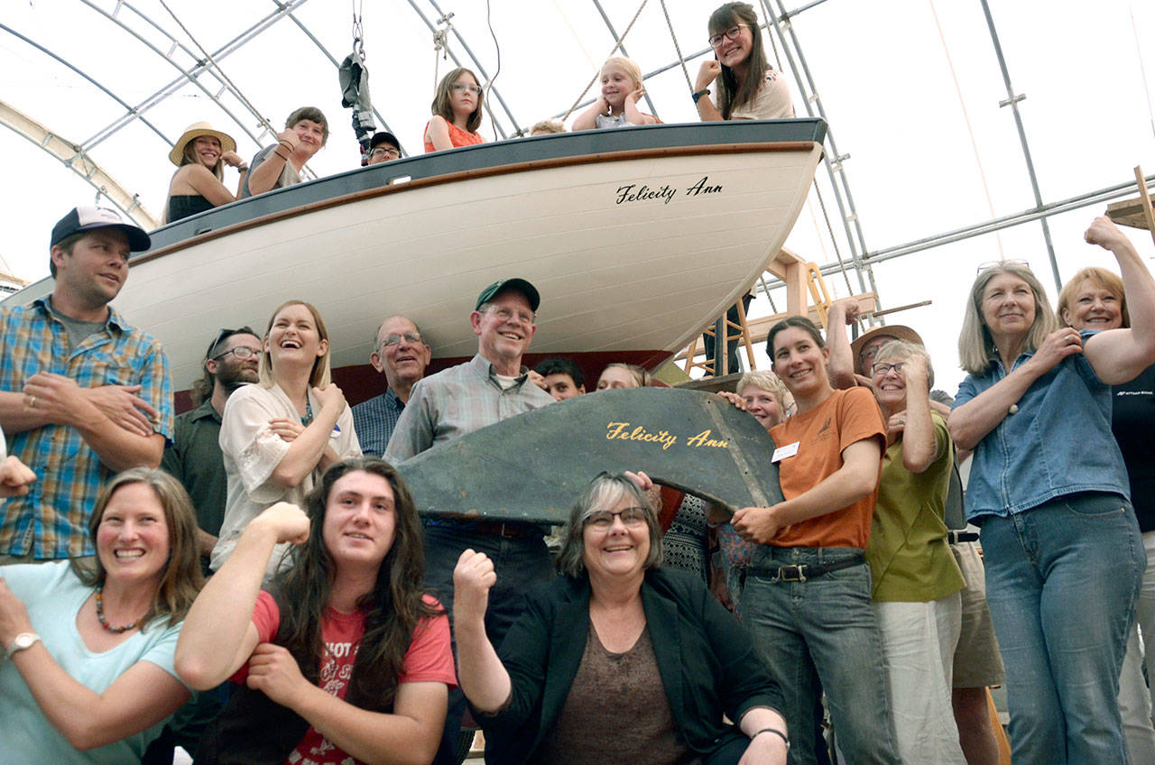 Members of the Northwest School of Wooden Boat Building and the Community Boat Project celebrate the now restored Felicity Ann, a boat made famous as the vessel sailed by Ann Davison, the first woman to sail solo across the Atlantic. (Cydney McFarland/Peninsula Daily News)