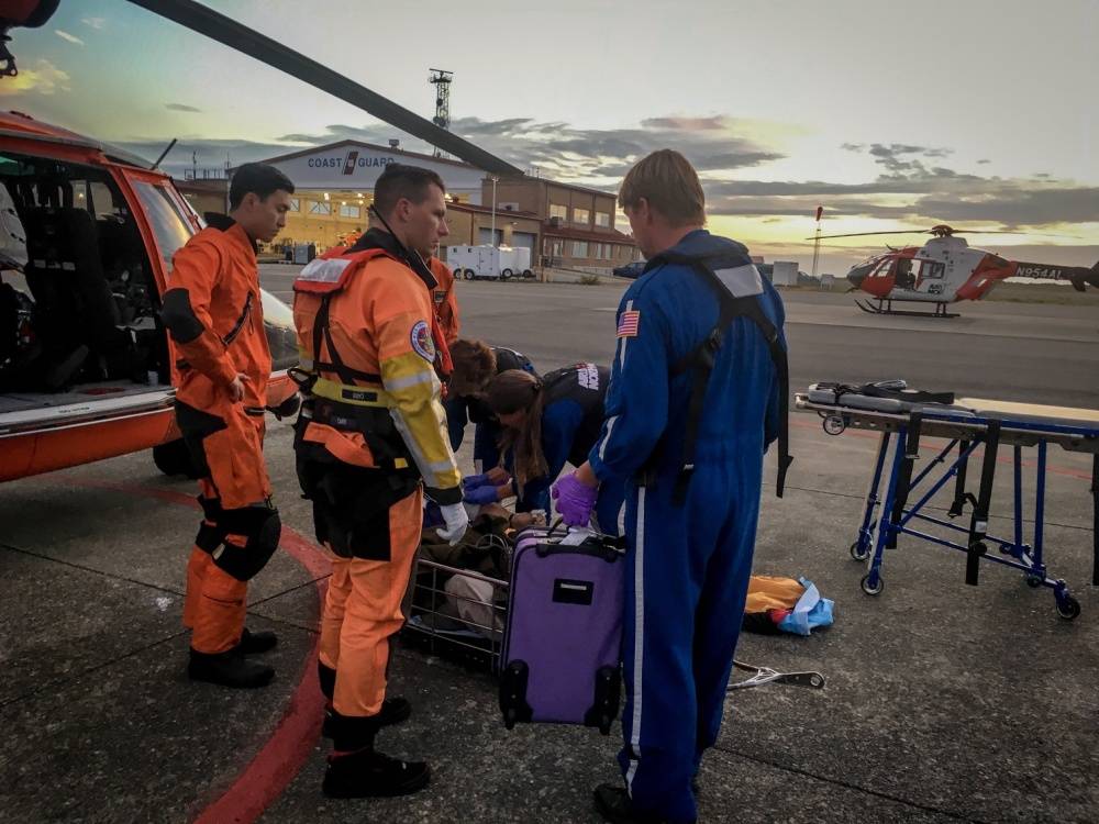 Coast Guard MH-65 Dolphin aircrew members from USCG Air Station Port Angeles share patient information with medics from Airflight Northwest on Monday evening. (Petty Officer 1st Class Levi Read/U.S. Coast Guard)