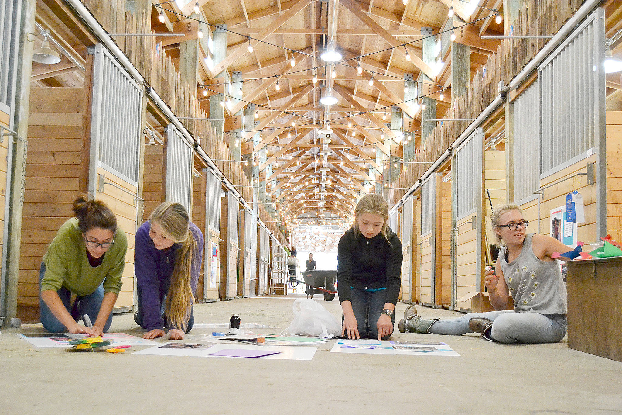 Members of the Silver Spurs 4-H Club — from left, Ashlyne Money, 16; Sierra Steffen, 12; Marissa Steffen, 10; and Lisi Hanson, 15 — design posters for their horses’ stalls Monday in a horse barn at the Clallam County Fairgrounds. Their group will show 18 horses throughout the fair, which runs through Sunday. (Matthew Nash/Olympic Peninsula News Group)