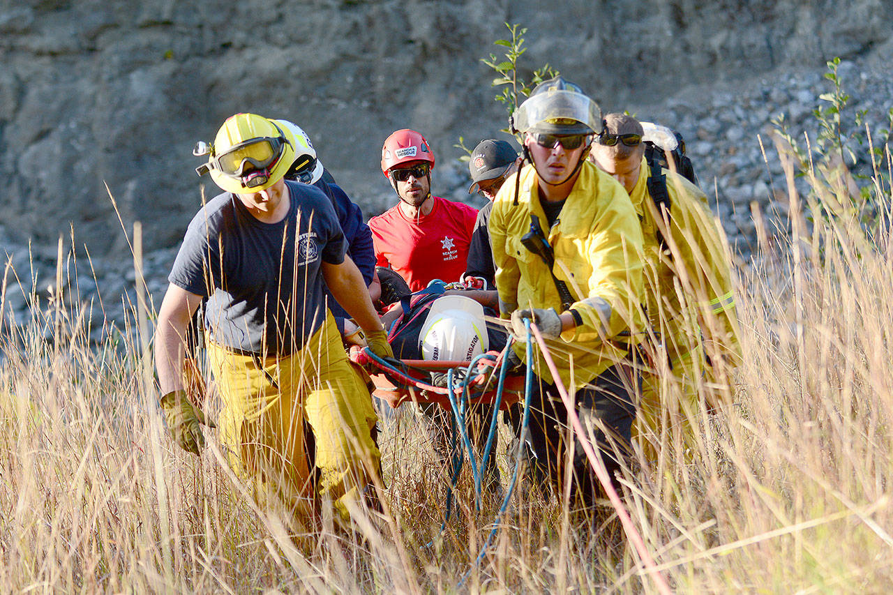 First responders help hiker Brandon Field, 22, of Port Angeles after he fell down an embankment at the former Elwha Dam site Sunday afternoon. (Jesse Major/Peninsula Daily News)