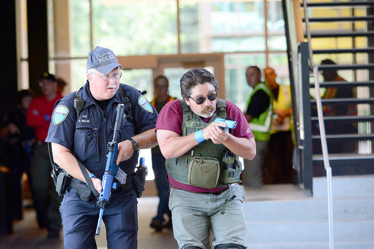 A Sequim police officer and Border Patrol agent move through Keegan Hall during an active shooter training at Peninsula College on Thursday. (Jesse Major/Peninsula Daily News)