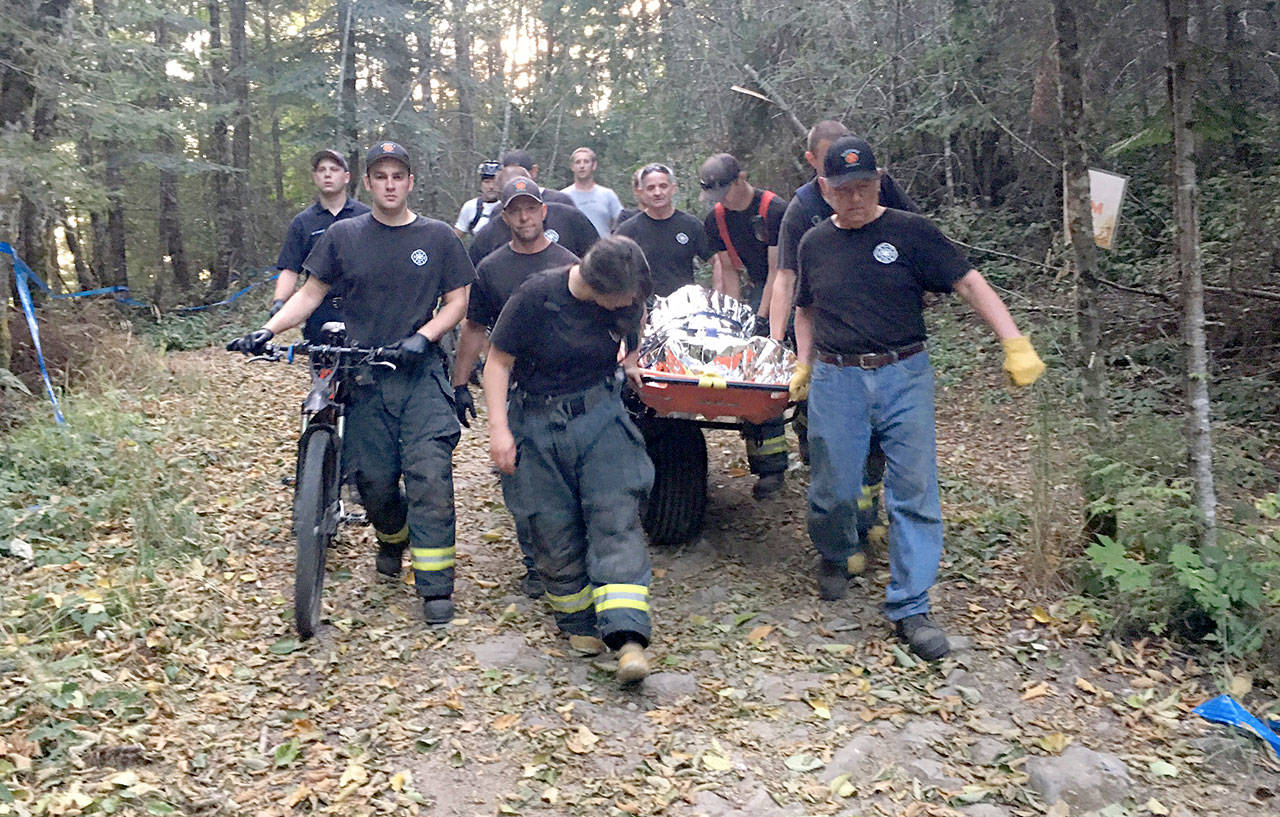 Clallam County Fire District No. 2 crew members help transport a bicycle accident victim out of the woods off Dry Hill, up Walkabout Way Road off U.S. Highway 101 near Port Angeles. (Clallam County Fire District No. 2)
