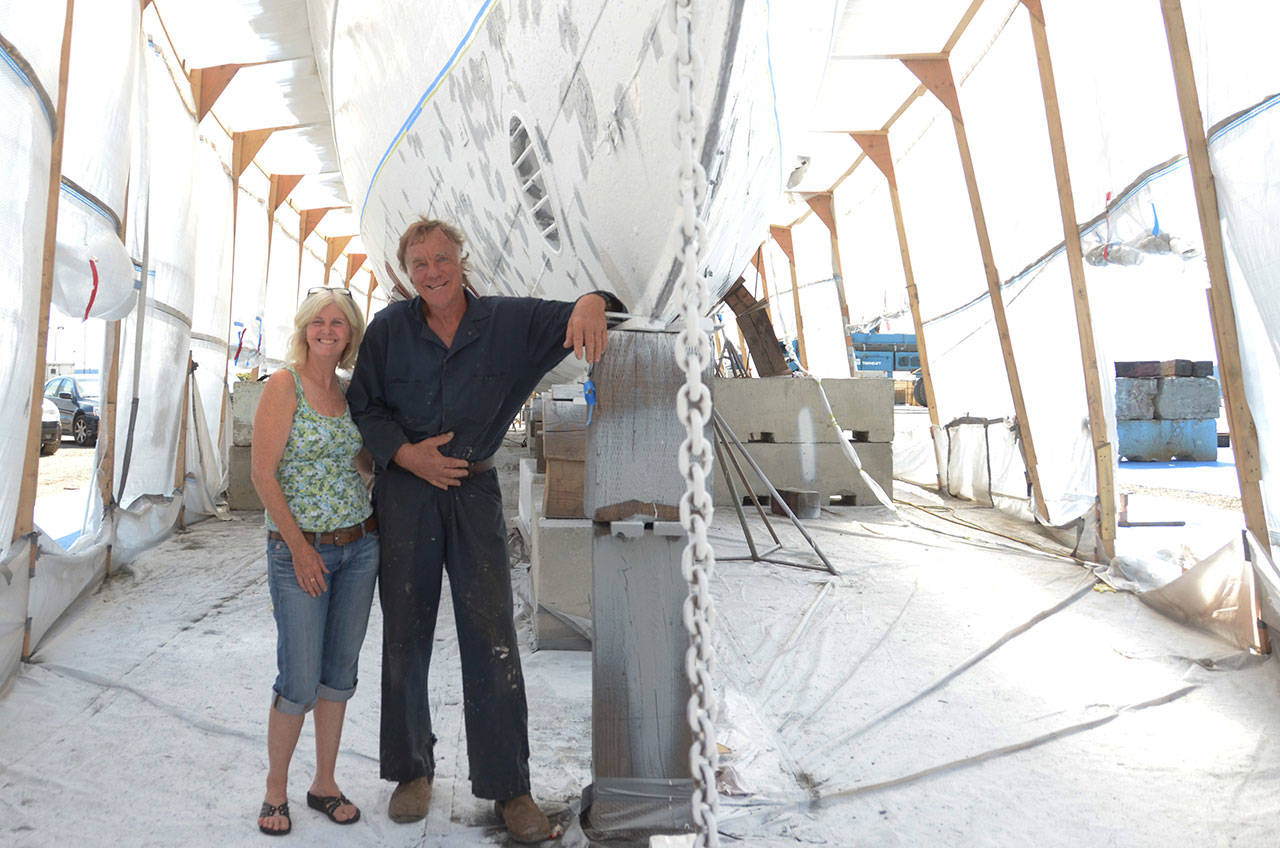 Melissa Lynch and Christian Lint stand next to the steel hull of the El Primero, a historic yacht built in 1893 in San Francisco and currently being restored in the Boat Haven boatyard in Port Townsend. (Cydney McFarland/Peninsula Daily News)