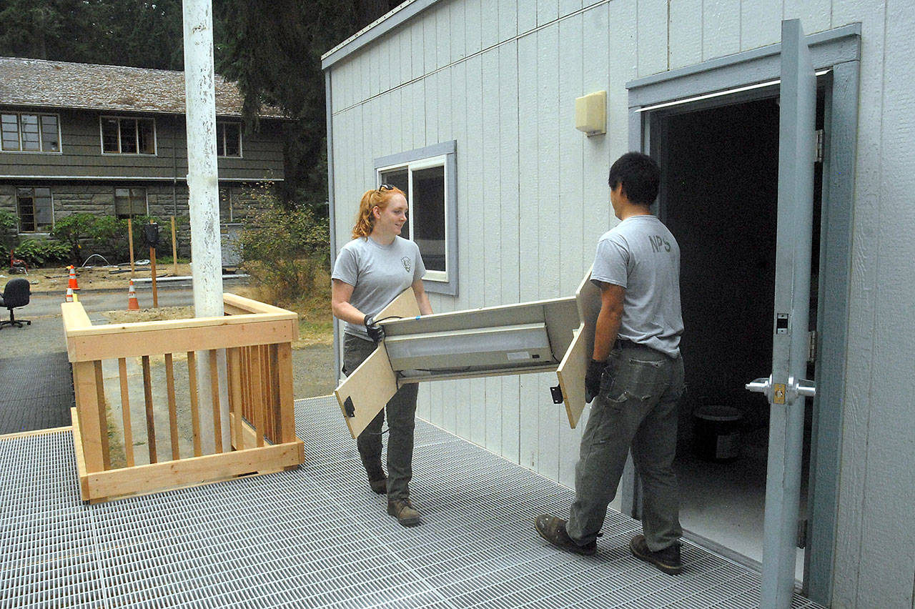 Olympic National Park maintenance workers Kelli Hoine, left, and Kyle Jenkins carry office furniture Tuesday into a portable building that will serve as a temporary visitor center on the front driveway of the current park headquarters building on Park Avenue in Port Angeles. (Keith Thorpe/Peninsula Daily News)