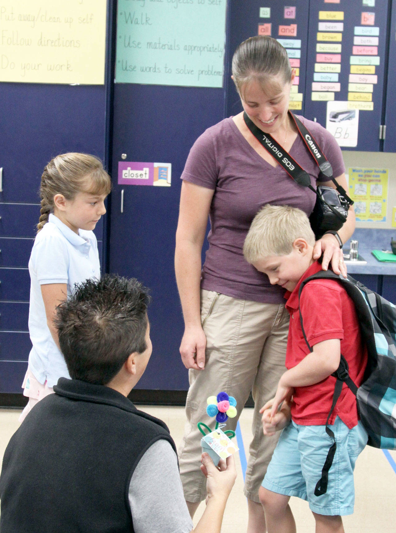 Alex Biss, right, is comforted by mom April as they meet Christine Chang, kneeling at left, Alex&rsquo;s first-grade teacher at Jefferson Elementary School in Port Angeles. Paige, a third-grader, looks on for her younger brother&rsquo;s special day. (Dave Logan/for Peninsula Daily News)