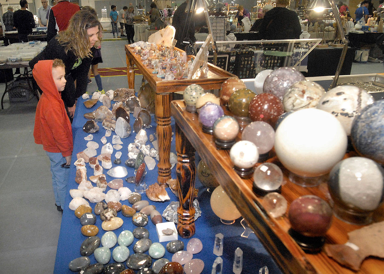 Julie Throop of Port Angeles and friend Brixton Martinez, 4, examine a table filled with rocks and gemstones operated by RT Crystals and Beads of Sequim during last year’s Rock, Gem Jewelry Show at the Vern Burton Community Center in Port Angeles. (Keith Thorpe/Peninsula Daily News)
