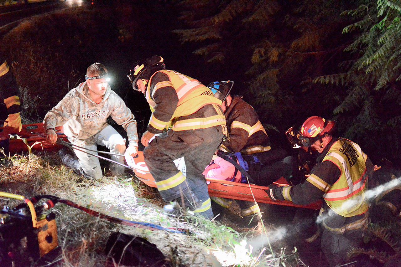 Three people were transported to Olympic Medical Center in Port Angeles following a two-vehicle collision on U.S. Highway 101 near Barnes Point at Lake Crescent on Wednesday evening. Shown are Clallam Fire District No. 2 first responders removing a victim from the wreck area. (Jay Cline/Clallam Fire District No. 2)