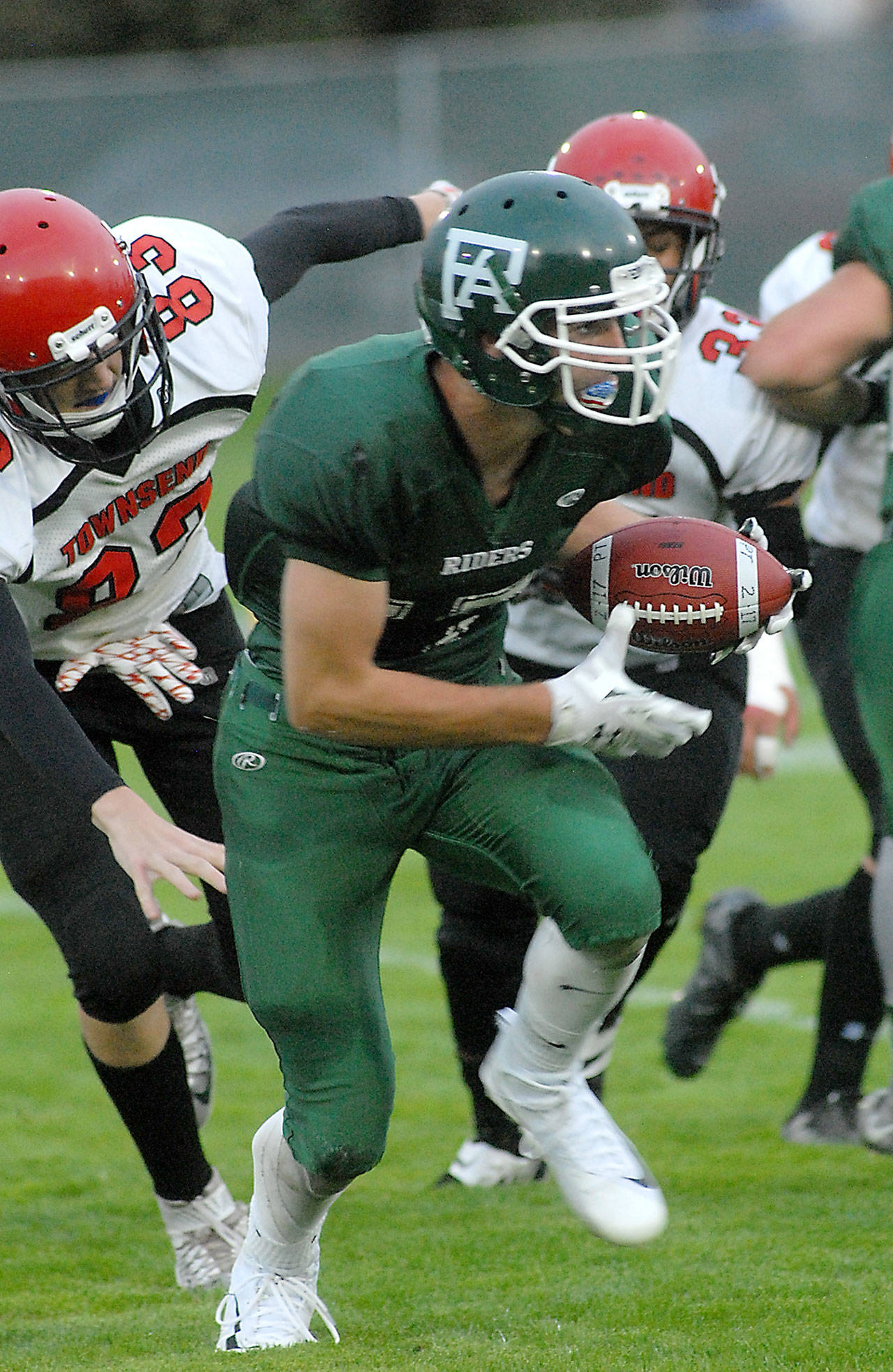 Port Angeles’ Garrett Edwards, center, carries the ball while avoiding the defense of Port Townsend’s Jaden Steinfort, left, and Jacob Boucher, rear, during the first quarter on Friday at Port Angeles Civic Field.                                Keith Thorpe/Peninsula Daily News