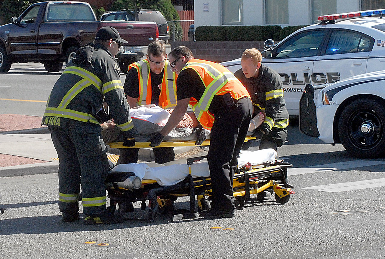 Emergency workers assist a pedestrian after the person was struck by a vehicle at the intersection of First and Race streets in Port Angeles on Tuesday. (Keith Thorpe/Peninsula Daily News)