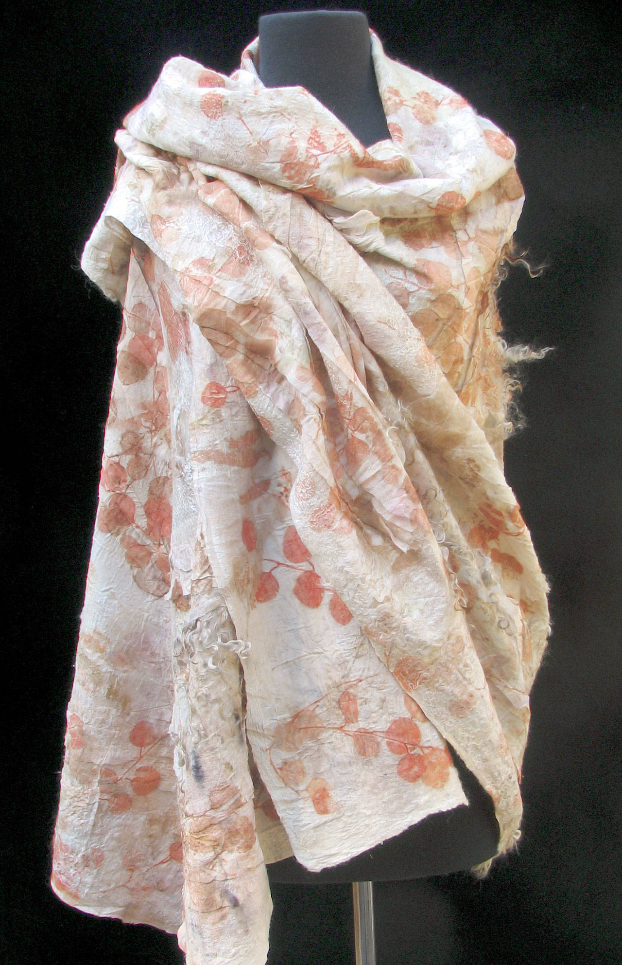 Michelle Johnson creates felted garments. This piece, a shawl entitled “Plant Dance,” has been created from various breeds of wool combined with silk using the nuno-felting process. It’s eco-printed with varieties of local fresh leaves and branches. Johnson says the materials were carefully gathered with the hopes of having the plants’ energy embrace the wearer.