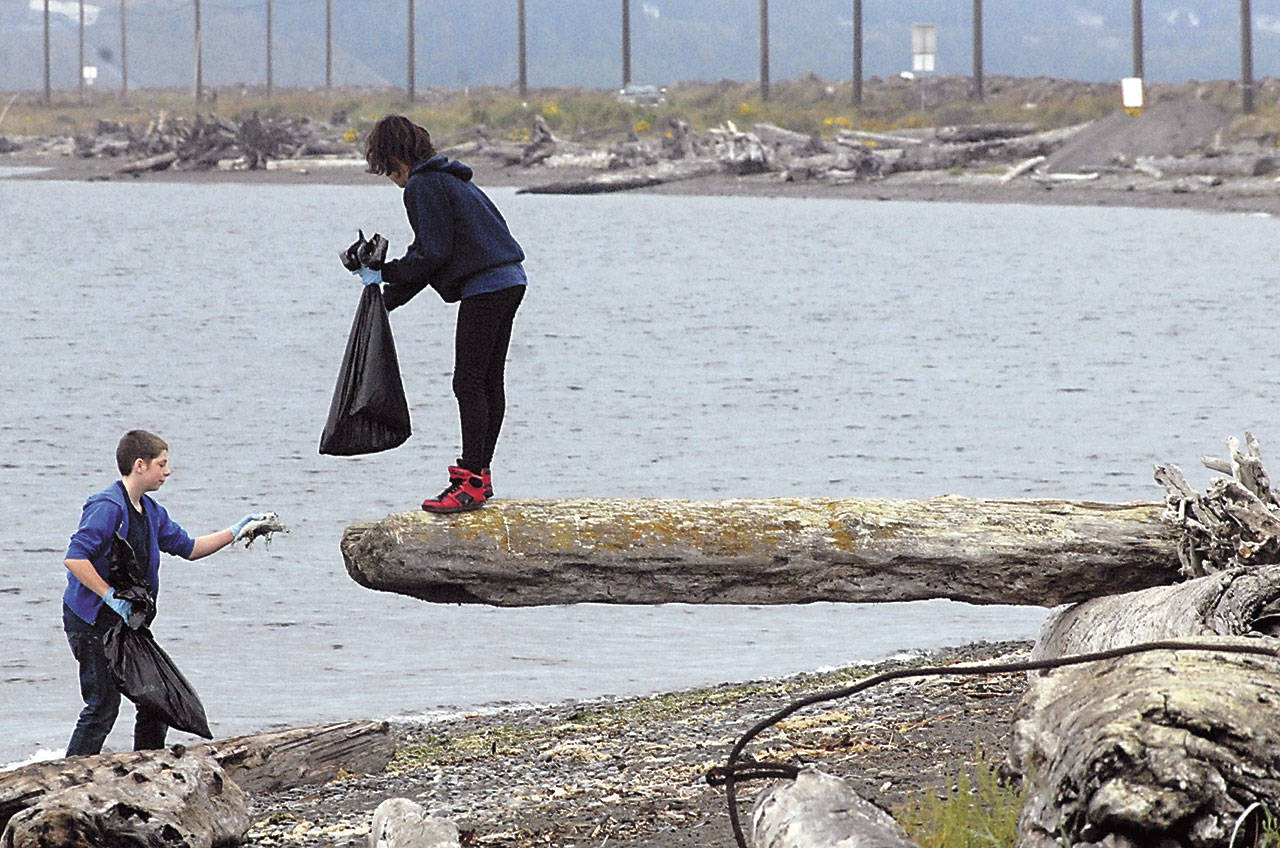Ethan Wood, then 15, left, shows a piece of collected beach trash to Sydney Evans, then 14, on Ediz Hook in Port Angeles during a beach cleanup outing as part of the 2015 International Coast Cleanup effort. (Keith Thorpe/Peninsula Daily News)