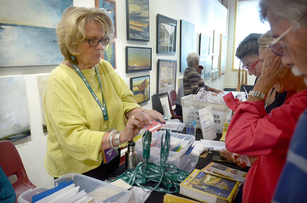 Port Townsend Film Festival volunteer Kathleen Holt hands out passes to Anne Virtue and Patrick Roach of Port Townsend, who are attending the festival for the first time this year. (Cydney McFarland/Peninsula Daily News)