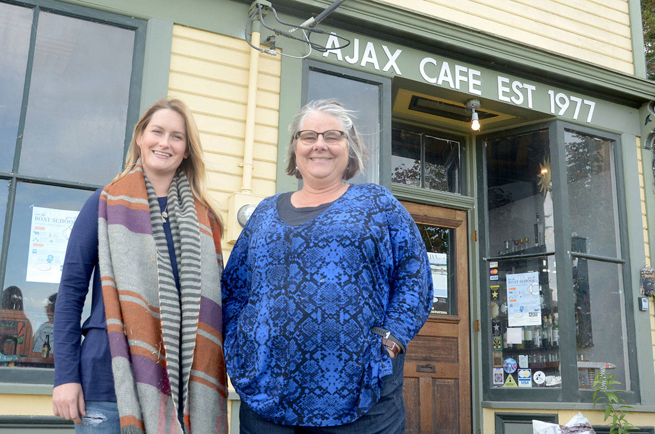 Northwest School of Wooden Boat Building Communications and Development Coordinator Christina Cogan, left, and Executive Director Betsy Davis stand in front of Ajax Cafe, which the boat school hopes to purchase thanks to a matching fund provided by anonymous donors. (Cydney McFarland/Peninsula Daily News)