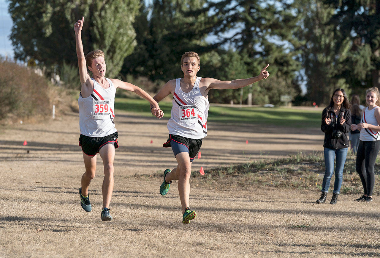 Port Townsend’s Nathan Cantrell, left, and Gabe Petrick, join hands and cross the finish line side-by-side to win the varsity boys race Wednesday at Port Townsend Golf Course.                                Steve Mullensky/for Peninsula Daily News