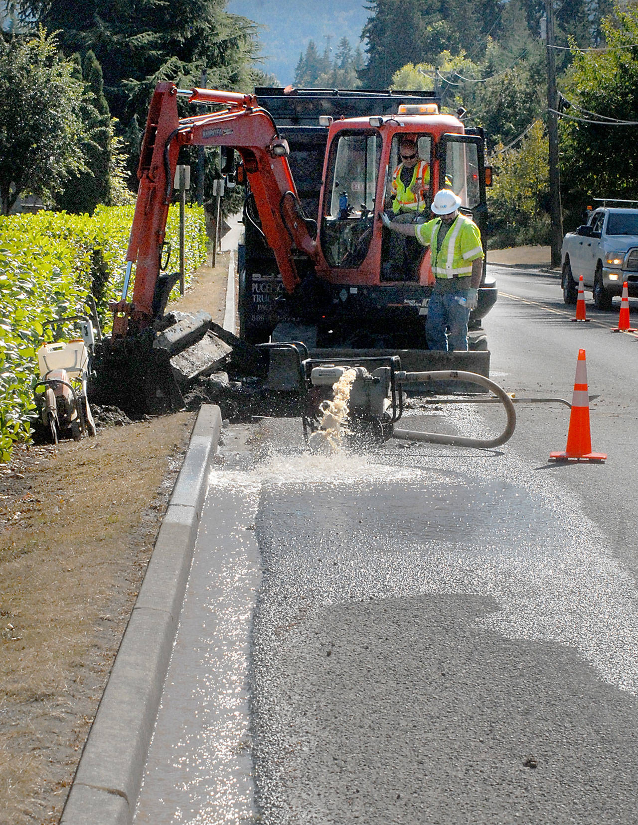A crew from Clallam County Public Utility District 1 drains water from an excavation after a water main break along Monroe Road east of Port Angeles on Thursday. (Keith Thorpe/Peninsula Daily News)
